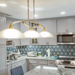 pendant lights over island, recessed lighting, under cabinet lighting in a kitchen with new modern appliances